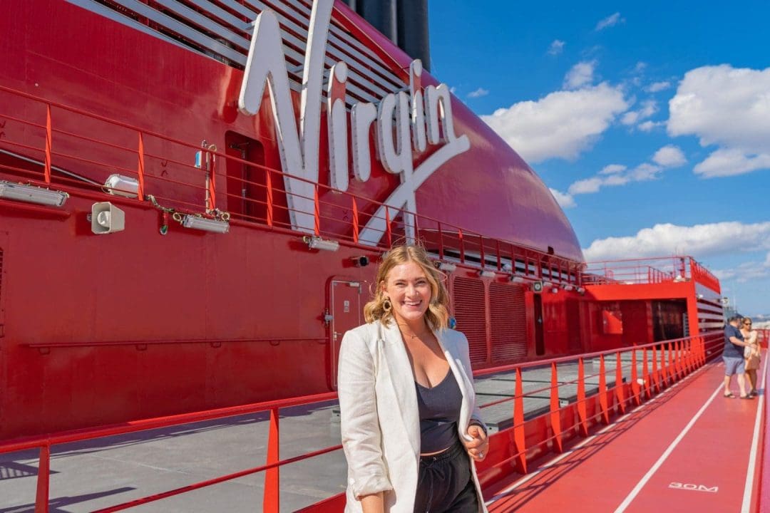 Kait smiling at the camera in front of the "virgin" sign on the Virgin Voyages Resilient Lady